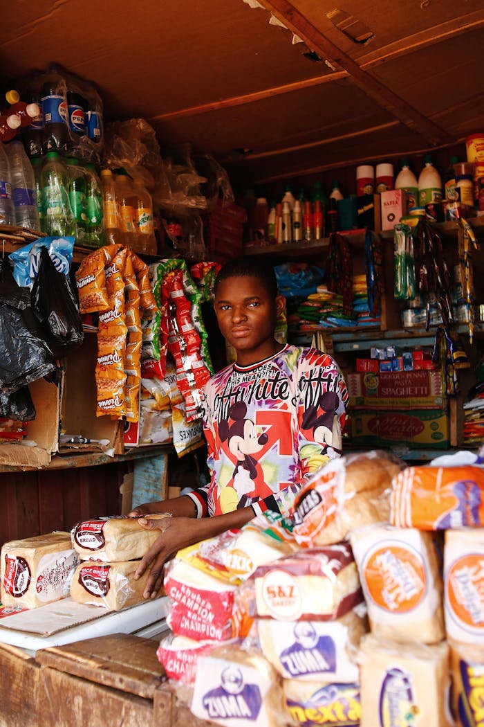 team-01 Young shopkeeper in a colorful Abuja market stall selling diverse groceries.